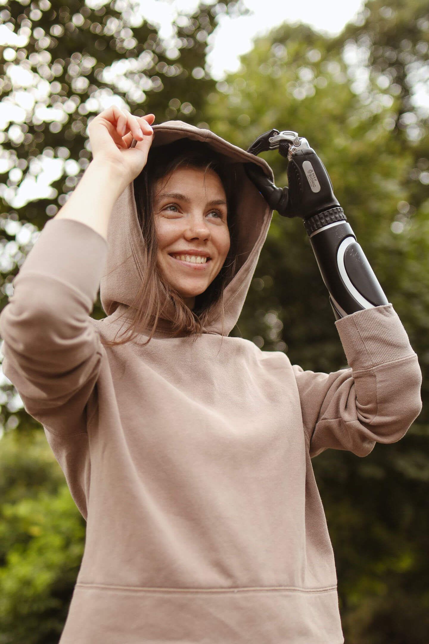 Person with prosthetic arm smiling and pulling on the hood from a hoodie
