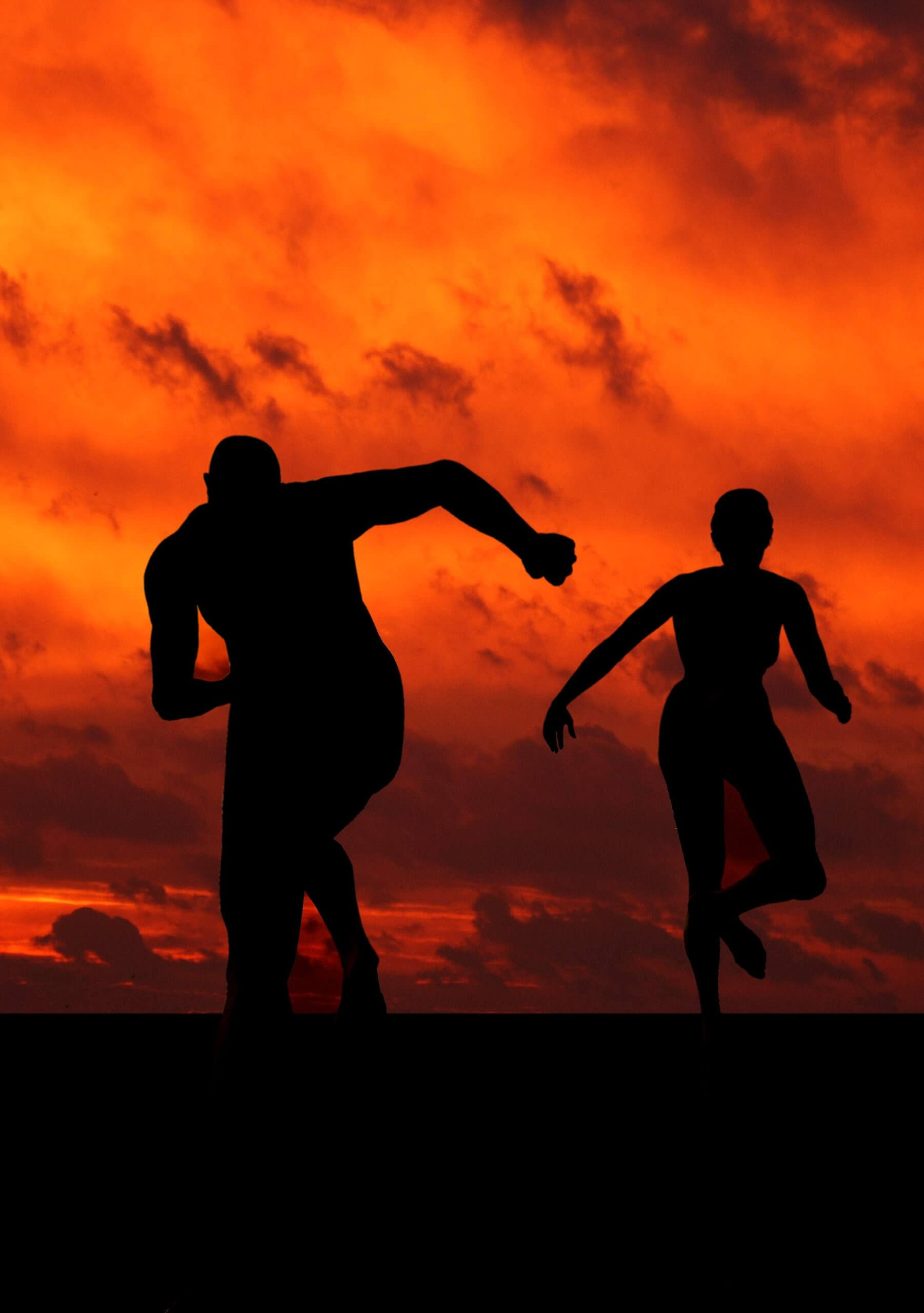 Silhouettes of two people running amidst a dark orange sky